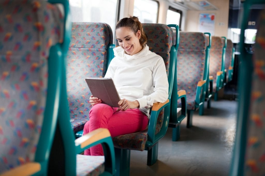 Cheerful young woman using tablet computer on the train